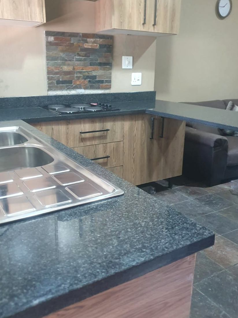 Close-up of the granite sink counter with an inset stainless steel sink and a polished front edge